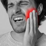 man holding his mouth and wincing in pain