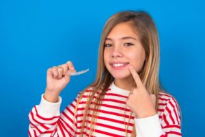 teen with invisalign pointing to her mouth